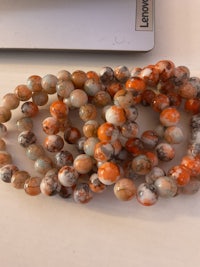 a bracelet with orange and gray beads sitting on top of a computer