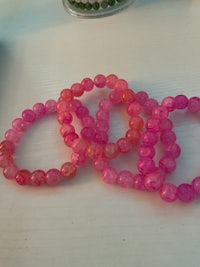 a group of pink and orange beaded bracelets on a table