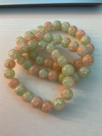 a bracelet of green and orange beads on a table