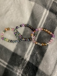 three multi colored beaded bracelets on a plaid blanket