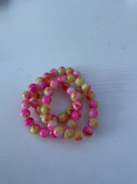 a pink and yellow beaded bracelet on a white surface